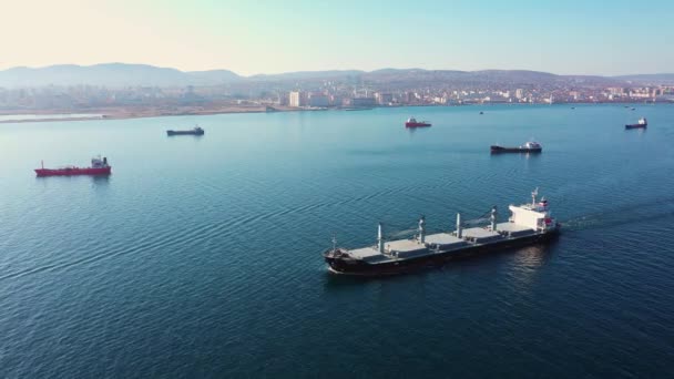Flygfoto efter ultra stora lastfartyg till havs lämnar hamnen vid solnedgången — Stockvideo