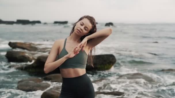 Леди позирует для камеры касаясь длинных волос против океанских волн — стоковое видео