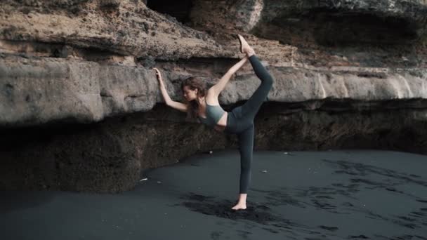 Fille ne s'étend près de montagne rocheuse sur le sable volcanique — Video