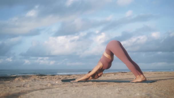 Mujer hace ejercicios de yoga, se extiende por la mañana con vista al océano, cámara lenta — Vídeos de Stock