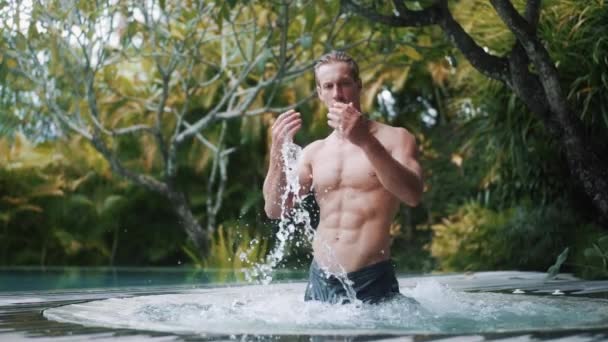 Shirtless man stands in jacuzzi at tropical resort vacation — Stockvideo