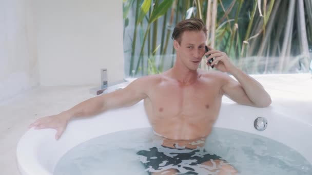 Homme heureux parle sur smartphone assis dans la baignoire à la maison — Video