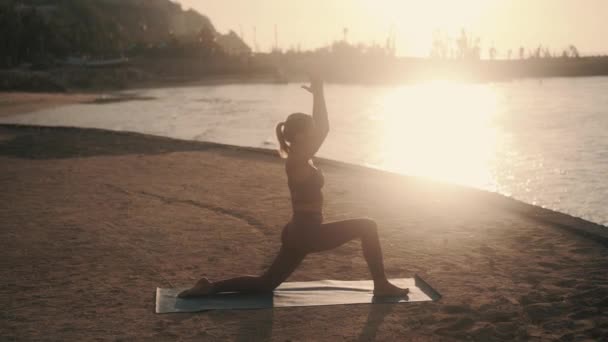 Silhouette de la femme faisant des étirements tôt le matin dans le rayon de soleil, au ralenti — Video