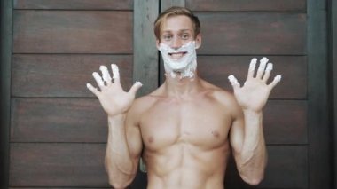 guy with shaving foam on face and fingers near vintage door