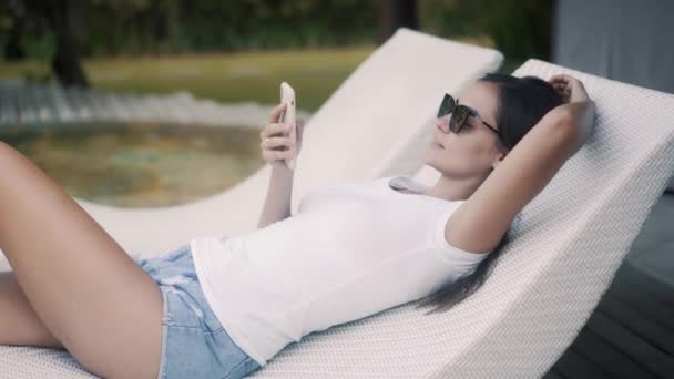 Femme tranquille utilise smartphone couché sur le canapé à la station — Video