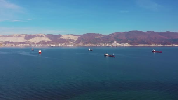 Vessels drift on calm blue ocean surface against hilly coast — Stock video