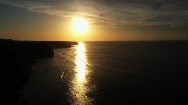 blurry golden sunset reflects on calm dark ocean surface