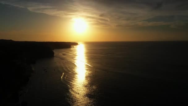 O pôr-do-sol dourado desfocado reflete na calma superfície do oceano escuro — Vídeo de Stock