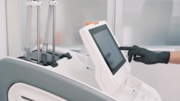 Close-up van de arts handen schakelt laserapparatuur voor de procedure, zijaanzicht — Stockvideo