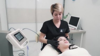 Beautician does facial massage to woman at cosmetology clinic.