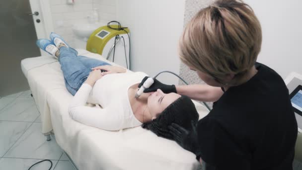 Вид сбоку, косметолог делает увлажняющую процедуру на декольте женщины в клинике — стоковое видео