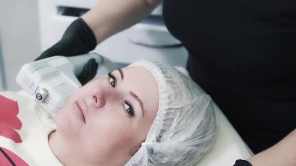 Γυναίκα κάνει διαδικασία ανύψωσης στο πρόσωπο με ειδική συσκευή στη σύγχρονη κλινική — Αρχείο Βίντεο
