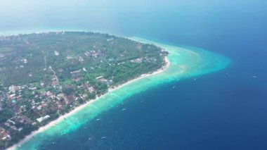 green tropical island with small buildings and sandy shore