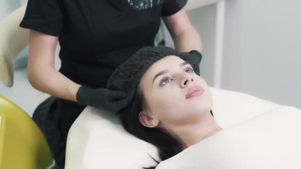 Косметик надевает одноразовый колпачок на пациента перед косметической процедурой — стоковое видео