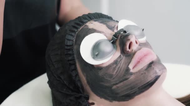 Close-up, vrouw in beschermende bril op carbon face peeling procedure in kliniek — Stockvideo