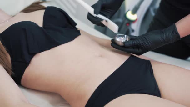 Красавчик руки наносит специальный гель на желудок женщины перед процедурой подъема — стоковое видео