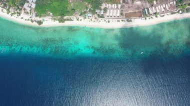 Sakin turkuaz şeffaf okyanus suyu ve dar kumsal