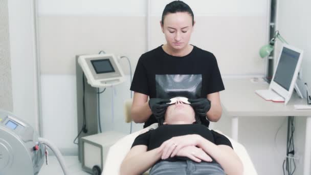 Esteticista coloca óculos de proteção nos olhos da mulher antes do tratamento facial — Vídeo de Stock