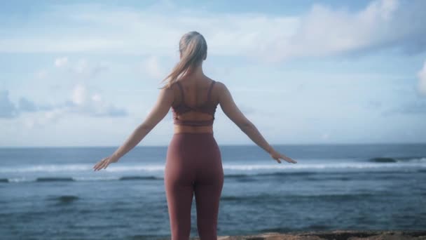 Chica de pie espalda levanta y baja las manos en la playa del océano — Vídeo de stock