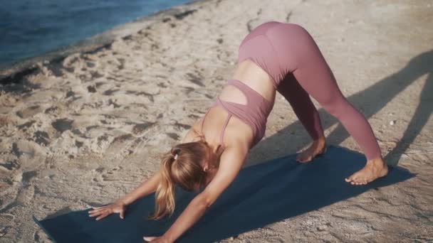 Блондинка в фіолетовому костюмі практикує пози йоги — стокове відео