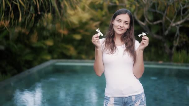 Brunette dame snuift plumeria bloem op tropische resort — Stockvideo