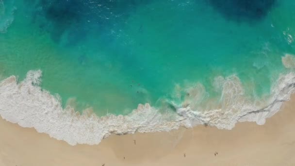 Vue aérienne du haut vers le bas de l'eau bleu azur, vagues océaniques se brisant sur la plage de sable 