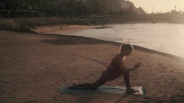 Kız yan açıyla dönüyor ve kobra yoga pozları veriyor.