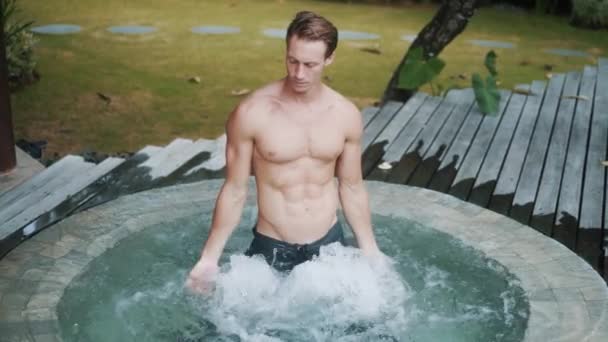 Handsome man stands in jacuzzi at tropical resort vacation, slow motion — Stock Video