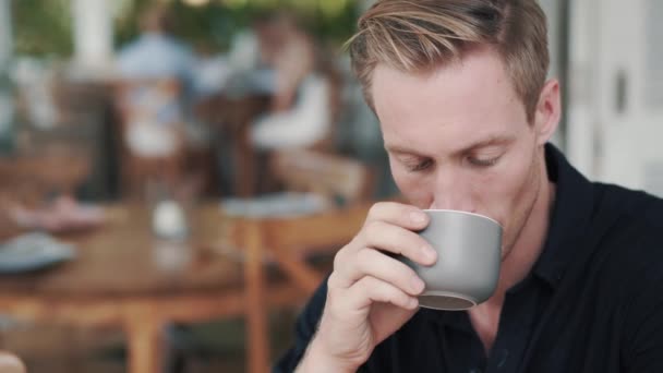 Retrato del hombre guapo bebiendo bebida caliente de la taza en la cafetería y sonriendo — Vídeos de Stock