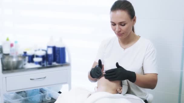 Esthéticienne en gants fait massage facial anti-âge à la jeune femme — Video