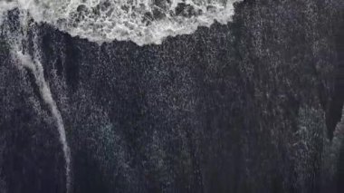 Volkanik kara kumsalın ve dev dalgaların güzel havadan görünüşü.