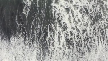 Volkanik kara kumsalın ve dev dalgaların güzel havadan görünüşü.