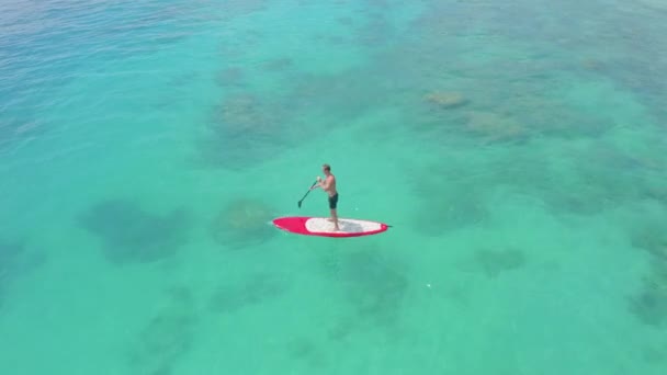 Красивый мужчина тренируется грести на белой доске для серфинга — стоковое видео