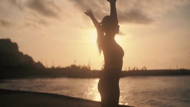 Silueta ženy cvičící jógu v časných ranních hodinách v paprscích slunce — Stock video