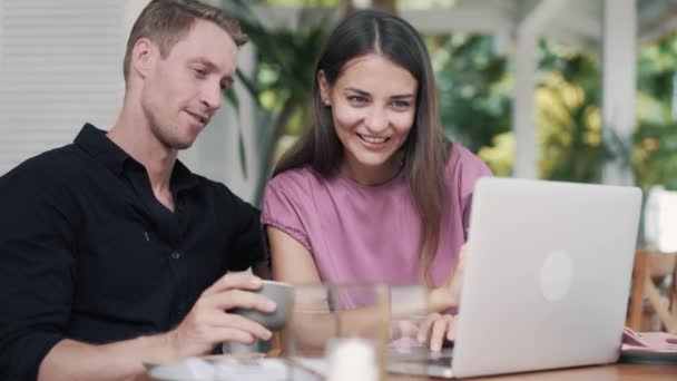 Hombre joven y mujer en la cafetería con estilo, el uso de la computadora portátil para el trabajo, chico bebe café — Vídeos de Stock