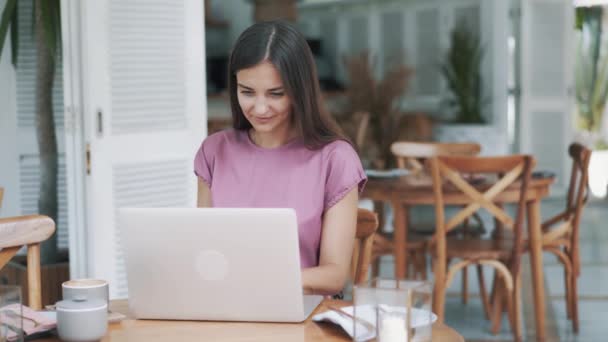 Freelancer bela jovem usa laptop moderno para o trabalho no café elegante — Vídeo de Stock