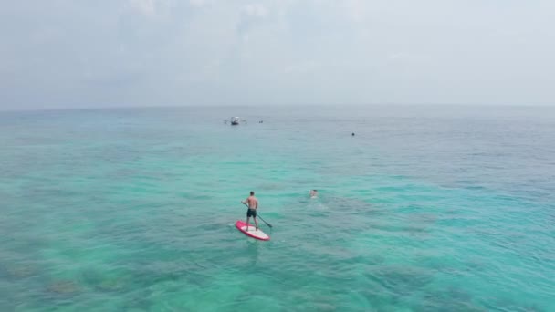 Flycam films fit man practising Stand Up Paddle on ocean — Stock Video