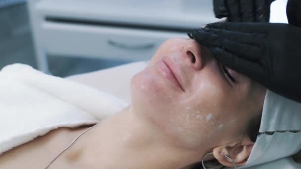 Close up, beautician in gloves makes anti-aging facial massage to young woman — Stock Video