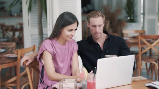 Guy et fille dans un café élégant, utiliser un ordinateur portable, boire du café, rire, vidéo drôle — Video
