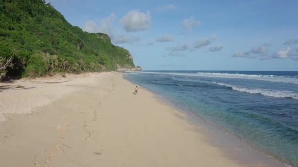 Vue aérienne athlète court seul sur la plage de sable, océan et montagnes en arrière-plan 
