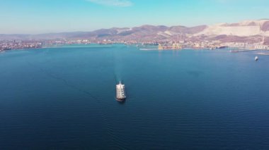 white cargo vessel sails crossing blue ocean against coast