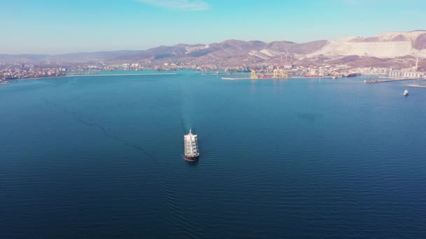 Біле вантажне судно вітрило перетинає блакитний океан на узбережжі — стокове відео