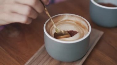 Yaklaş, bir fincan kahve, kadın eli içeceğe esmer şeker koyar.