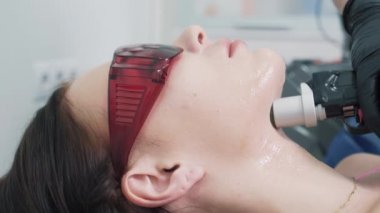 Güzellik uzmanının yüzü lazerle düzeltirken yandan görünüşü