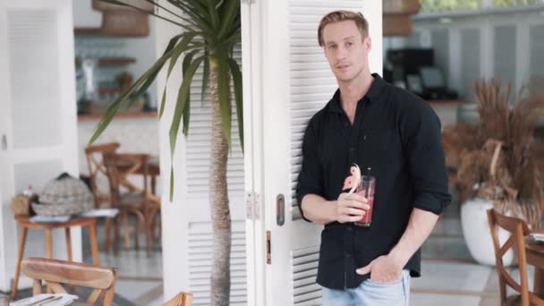 Brutal homme boit du jus de pastèque dans un café moderne avec un bel intérieur blanc — Video