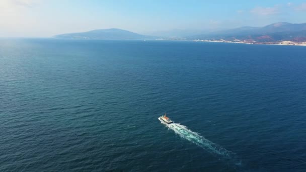 Luchtfoto van een klein schip dat langs de baai vaart, bergen op de achtergrond — Stockvideo