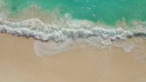 Vue aérienne du haut vers le bas de la plage de sable blanc avec de l'eau azurée, des vagues océaniques mousseuses  