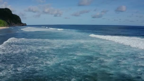 Vista aérea del océano con hermosas olas onduladas espumosas, montaña en el fondo — Vídeo de stock