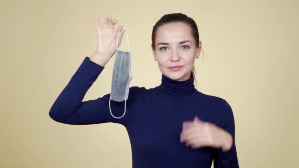 Jovem mulher segura máscara médica em suas mãos e mostra gesto polegares para cima — Vídeo de Stock