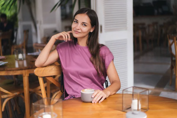 Portretul unei femei frumoase care bea băutură fierbinte din ceașcă în cafenea și zâmbind Imagini stoc fără drepturi de autor